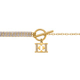 A detailed close-up studio shot focusing on the frontal closure of the Escada Diana bracelet, highlighting the polished golden t-bar toggle, the ring connection, and the crystal-paved edge of the suspended EE monogram charm.