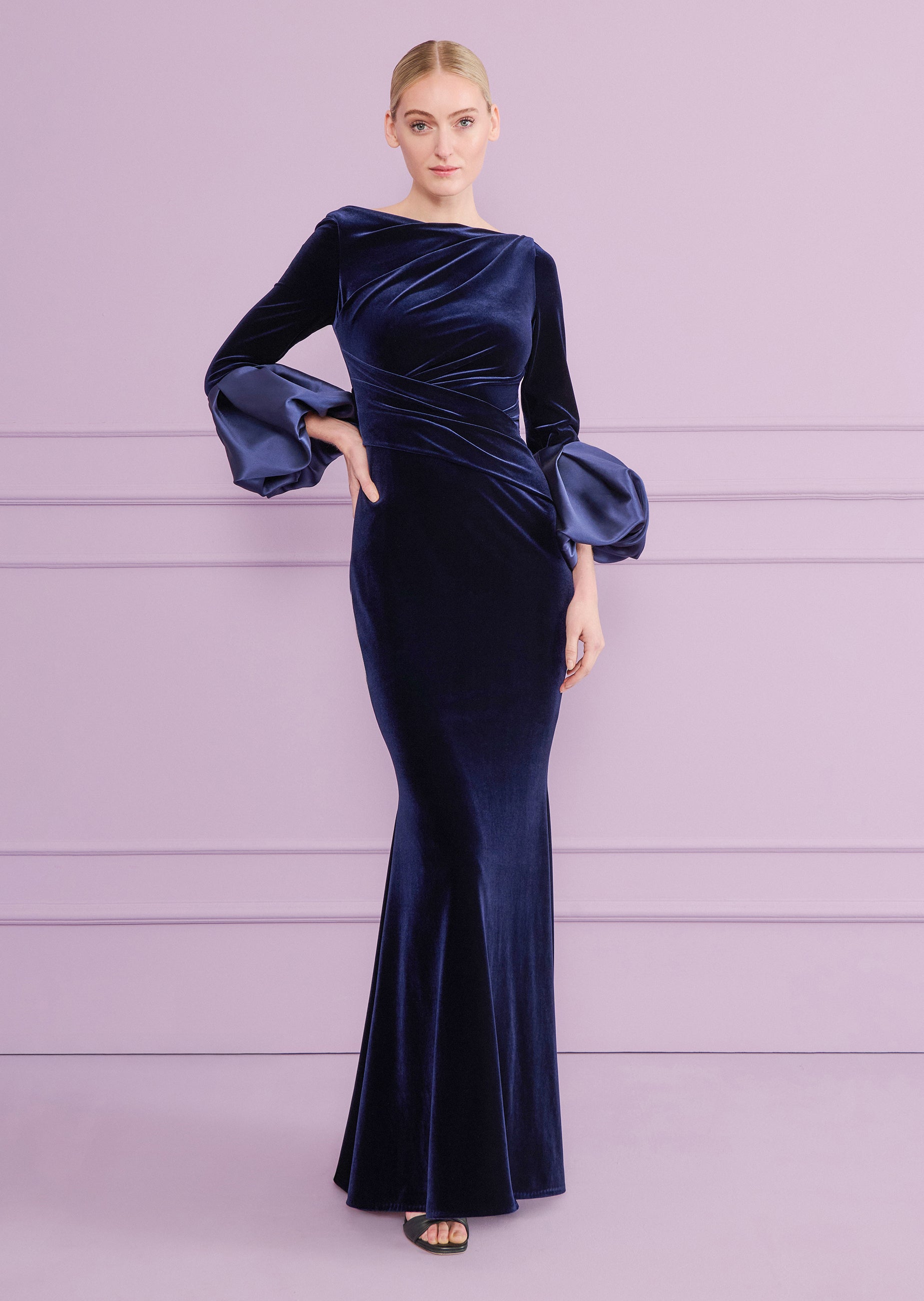 Navy velvet long dress with a boat neck, draped bodice, and long sleeves with voluminous satin puffed cuffs.