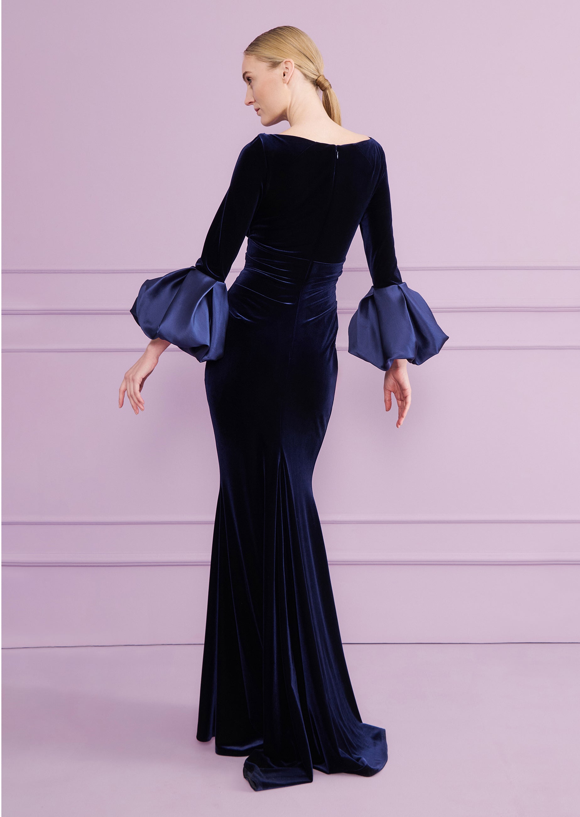 Dark blue velvet long dress with a scoop neckline, long sleeves, and voluminous navy satin cuffs. Fitted, with a flared hem.