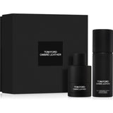 Tom Ford Noir Extreme gift set showcasing a large ribbed gold presentation box with a centered black logo square, a sleek rectangular translucent black perfume bottle with a gold cap, and a matching black cylindrical travel atomizer.