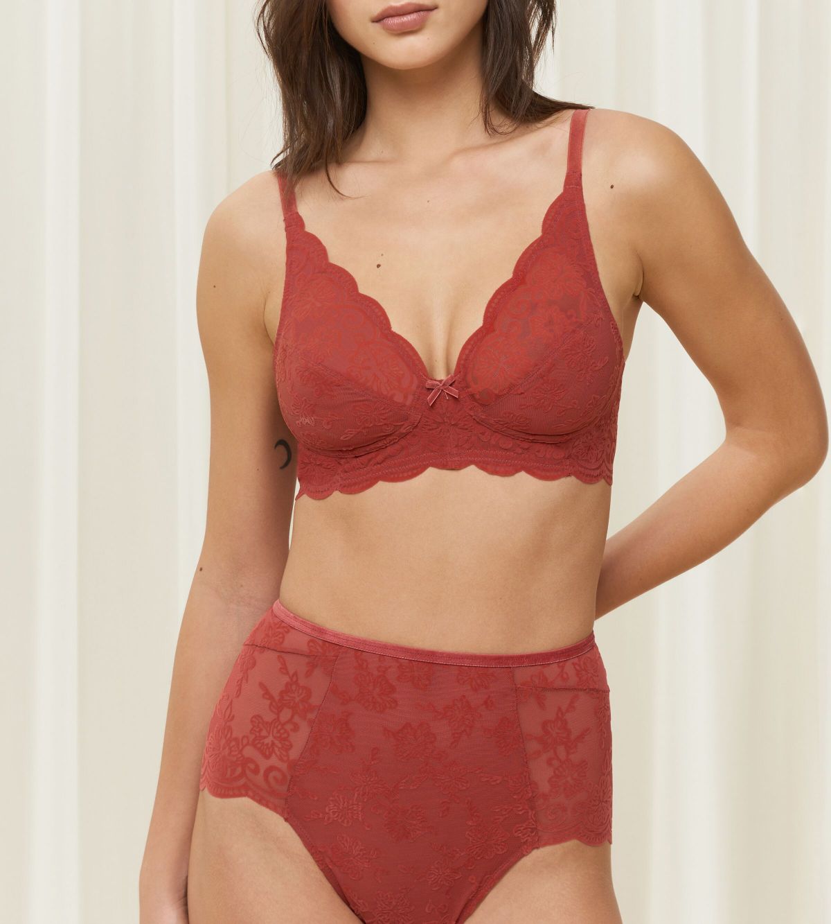 Triumph Amourette 300 Rococo non-wired bra in mannish red model front view, showcasing the intricate floral lace and wireless cup design. Order Online Today