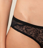 Triumph Amourette Charm Brazilian panties in black lace model close-up view, detailing the cheeky cut and flat-seam design. Shop Online at Blue Salon Qatar