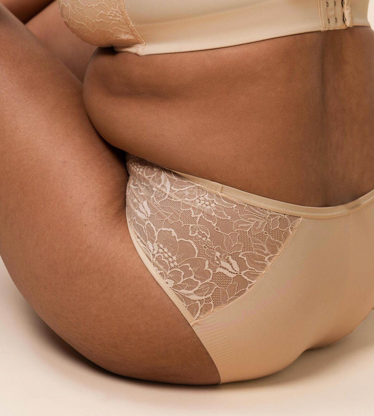 Triumph Amourette Charm maxi panties in light beige showing second model sitting view, featuring the high-waist lace front and smooth microfiber back. Order Online Today