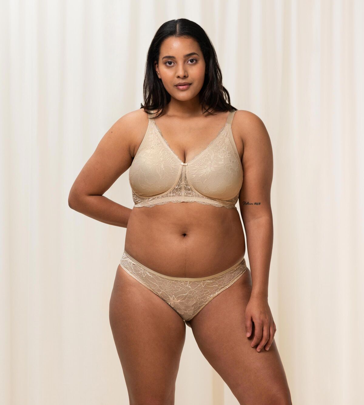 Triumph Amourette Charm non-wired bra in light beige second model full front view, showing the floral lace cups and plunge neckline. Available for Online Purchase