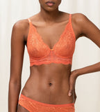 Triumph Amourette Charm non-wired bra in orange model front view, featuring floral stretch lace and a plunging neckline. Shop Online Today