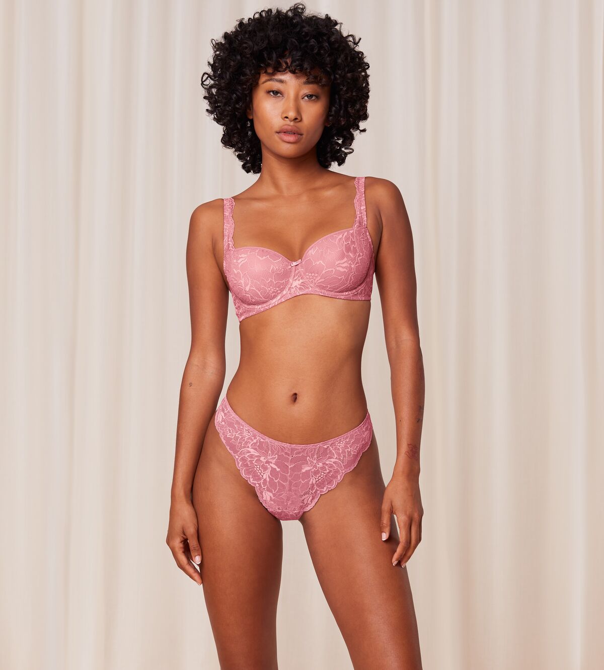 Triumph Amourette Charm wired padded bra in pink model full front view, showcasing the lace-covered cups and supportive underwired design. Order Online Today
