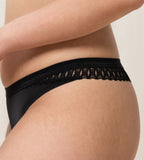 Triumph Aura Spotlight high leg string in black model close-up side view, showcasing the narrow sides and intricate lace detailing. Available Online at Blue Salon Qatar