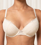 Triumph Aura Spotlight light beige  wired push-up bra model close-up view, showing the lace-overlaid padded cups and detailing design. Available Online Today.