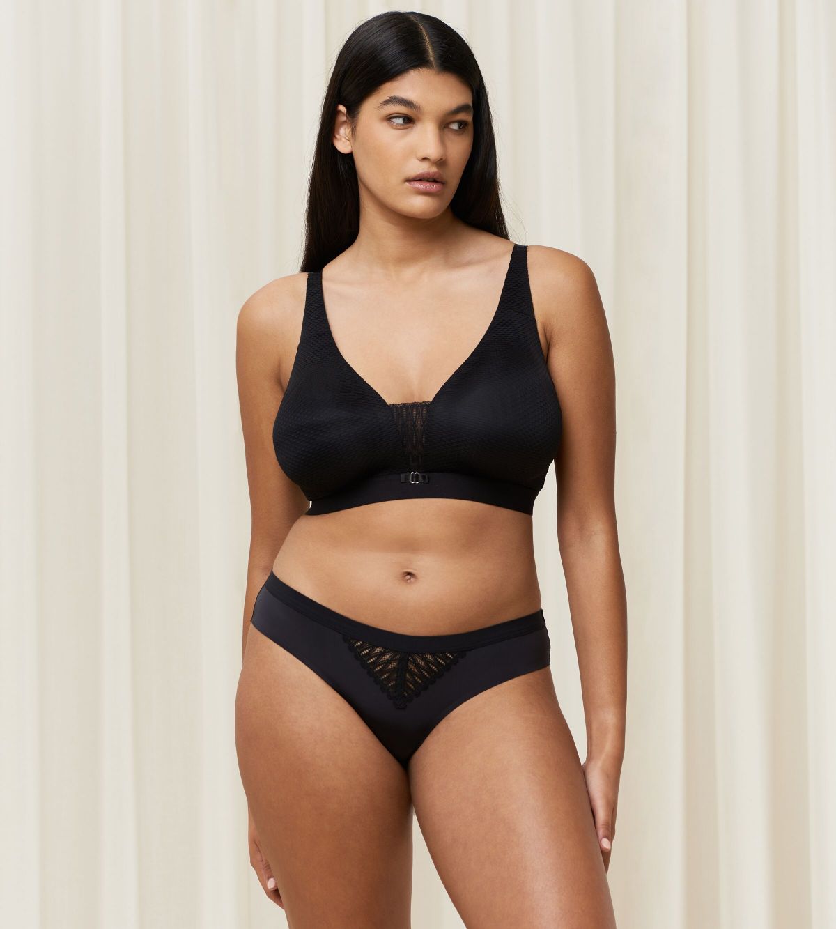 Triumph Aura Spotlight non-wired bra in black model full front view, showing the plunging lace neckline and comfortable wireless design. Find Now Online