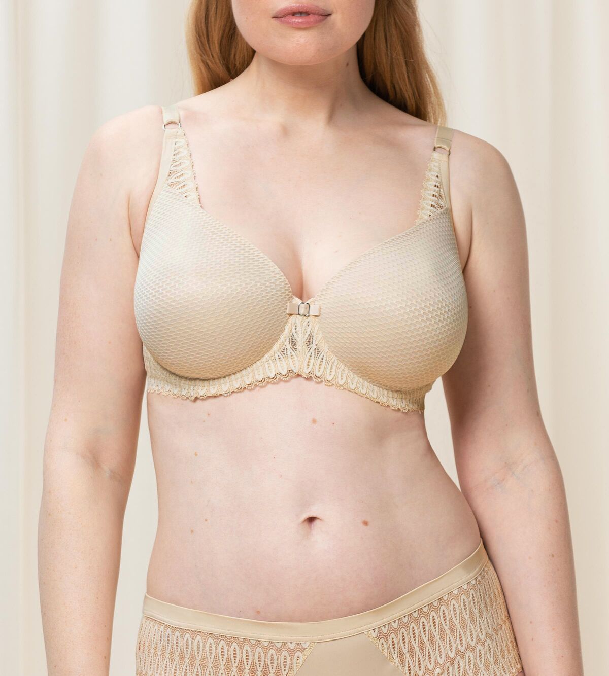 Triumph Aura Spotlight wired padded bra in light beige third model front view, showing the lace-overlaid cups and comfortable underwired design. Available Online