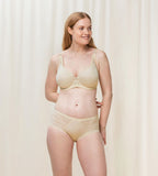 Triumph Aura Spotlight wired padded bra in light beige third model full front view, showing the lace-overlaid cups and comfortable underwired design. Available Online