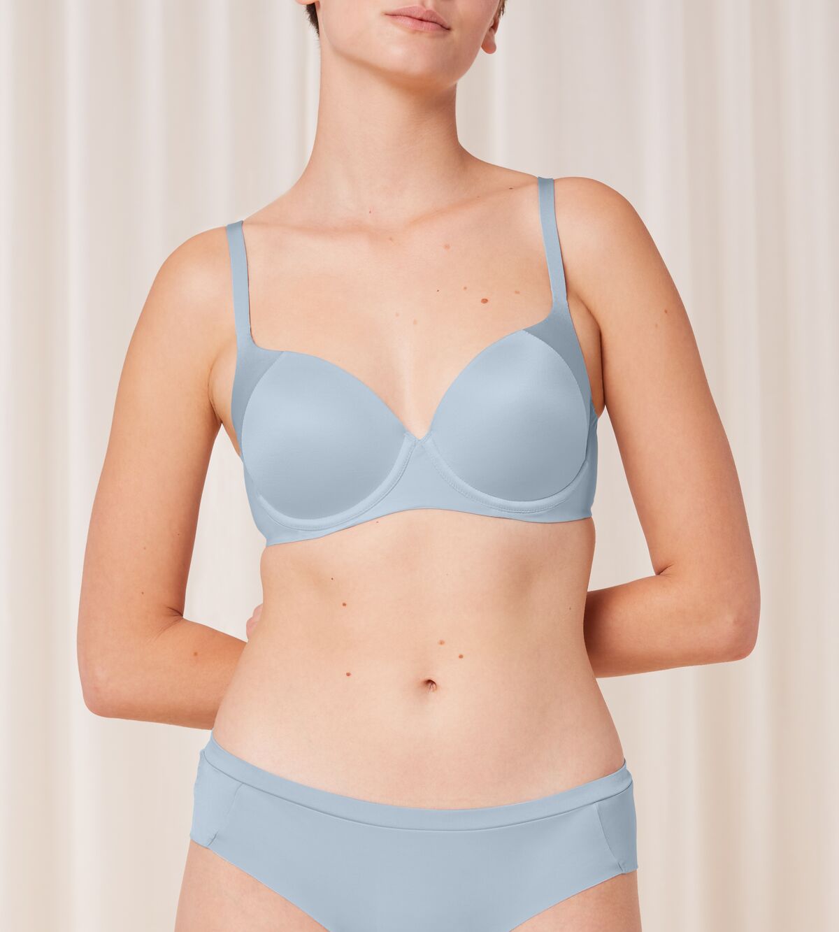 Triumph Body Make-Up Soft Touch light blue wired padded bra model front view, highlighting the smooth cups and soft-touch fabric texture. Shop Now Online