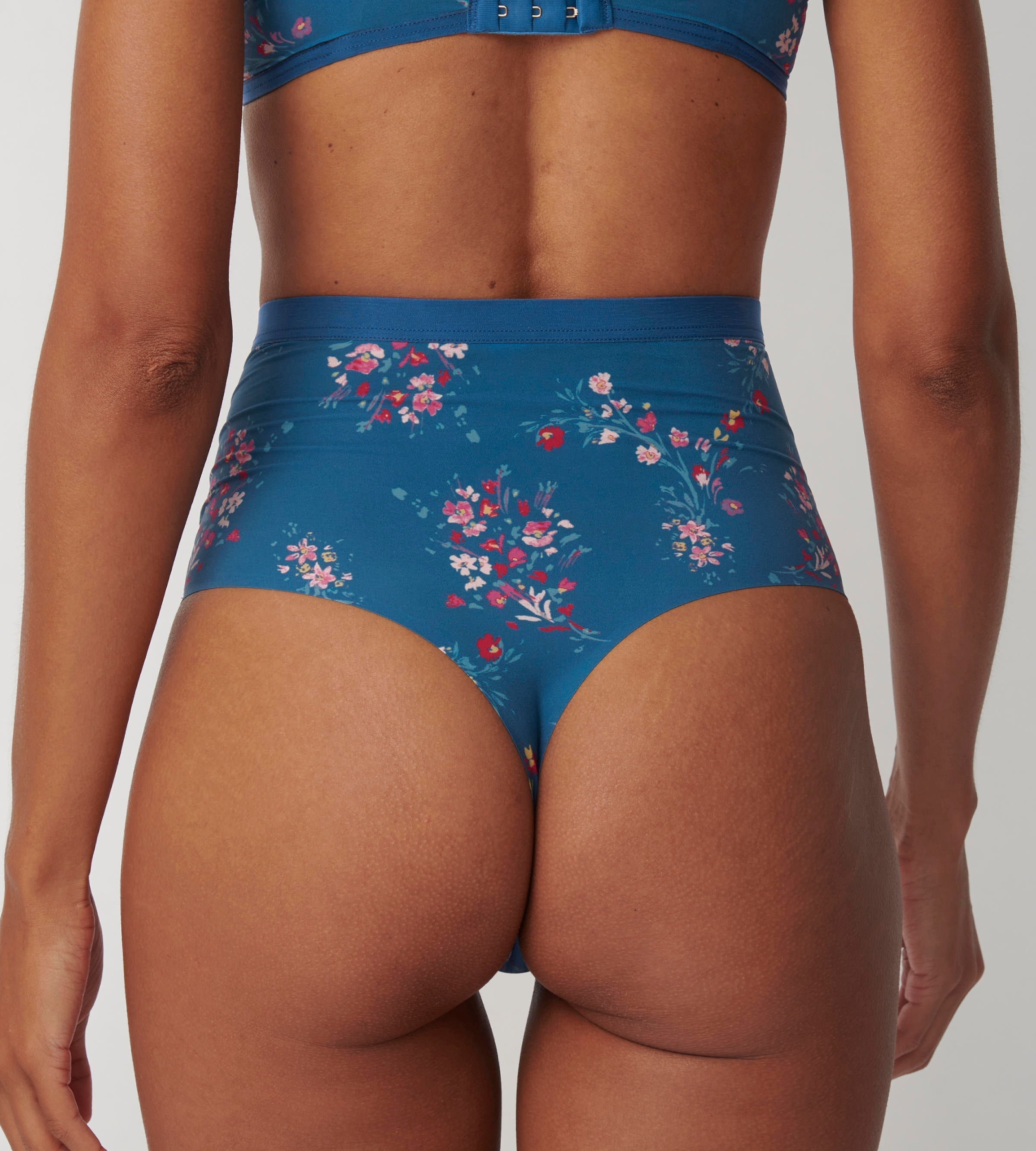 Triumph Electra Spotlight blue high waist thong model back view, highlighting the thong back and the floral mesh with high-waist silhouette. Available Online Today