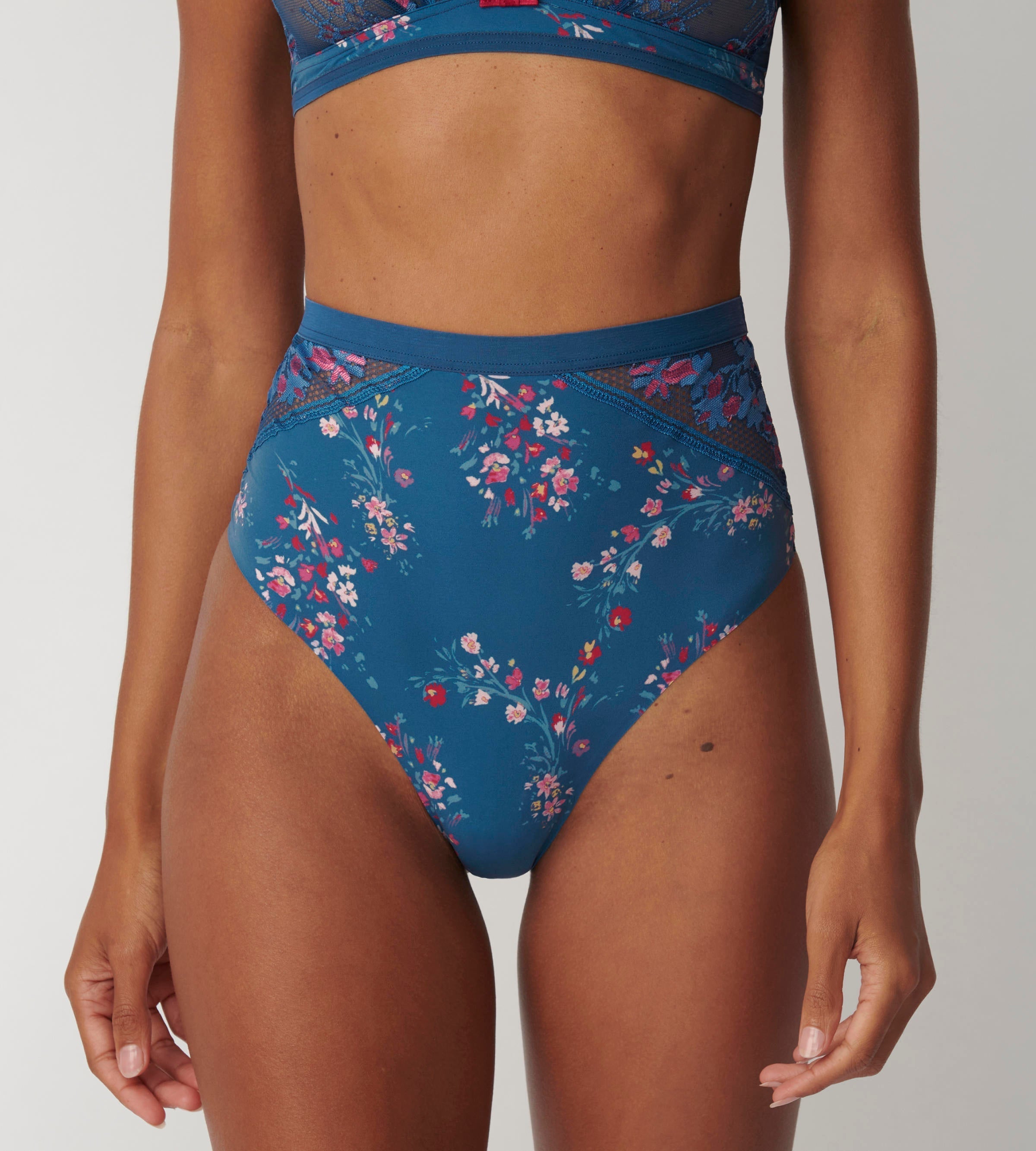 Triumph Electra Spotlight blue high waist thong model front view, highlighting the floral mesh and high-waist silhouette. Available Online Today