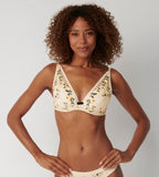 Triumph Electra Spotlight light beige wired padded bra model front view, showcasing the multi-colored floral lace cups. Available Online at Blue Salon Qatar