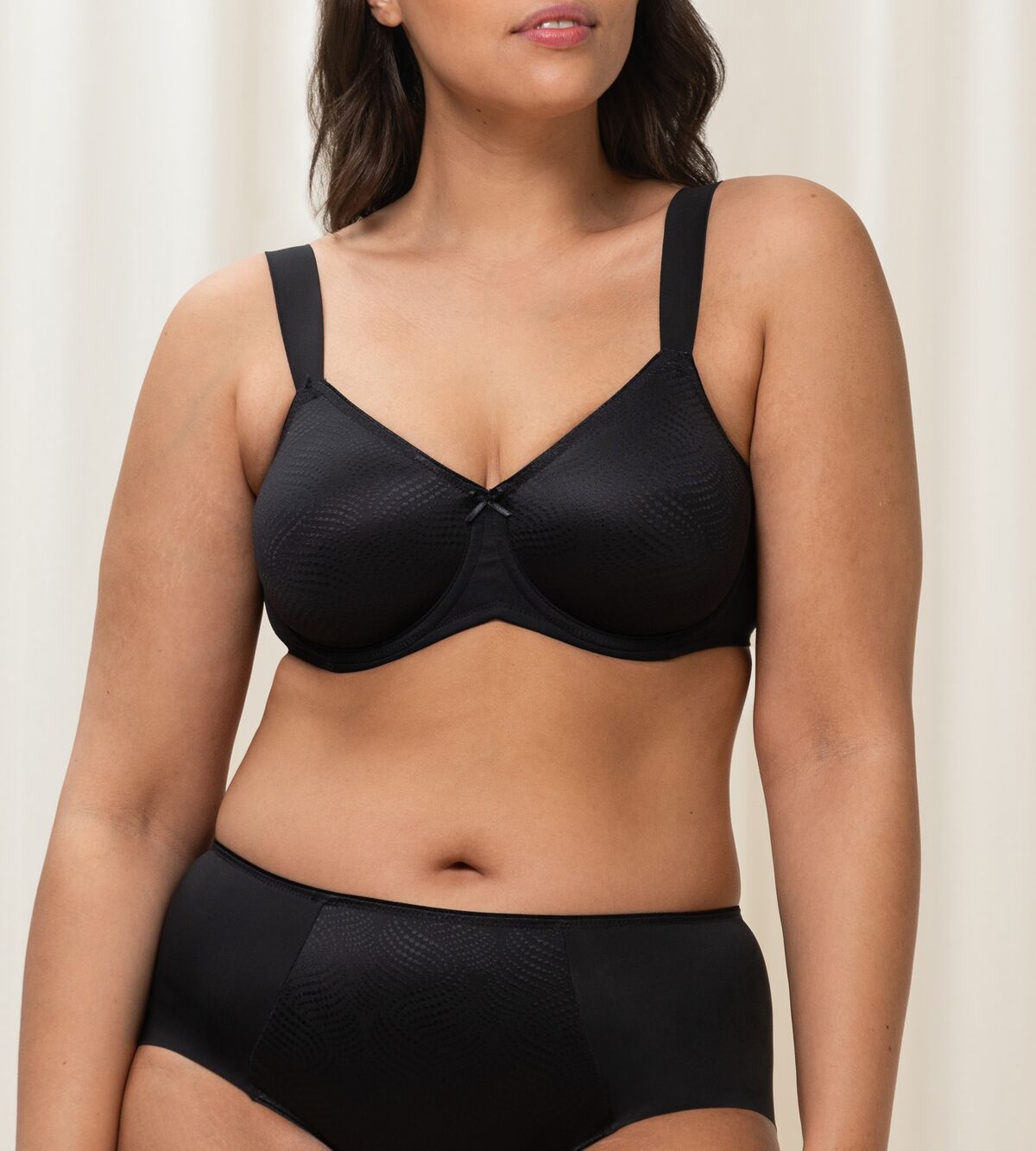 Triumph Essential Minimizer black underwired bra model front view, showing the shimmering jacquard pattern and wide adjustable straps. Shop the Latest Online