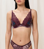 Triumph Lavish Spotlight burgundy wired padded bra Model front view, highlighting the detailed lace embroidery and elegant plunge fit. Now Online at Blue Salon Qatar