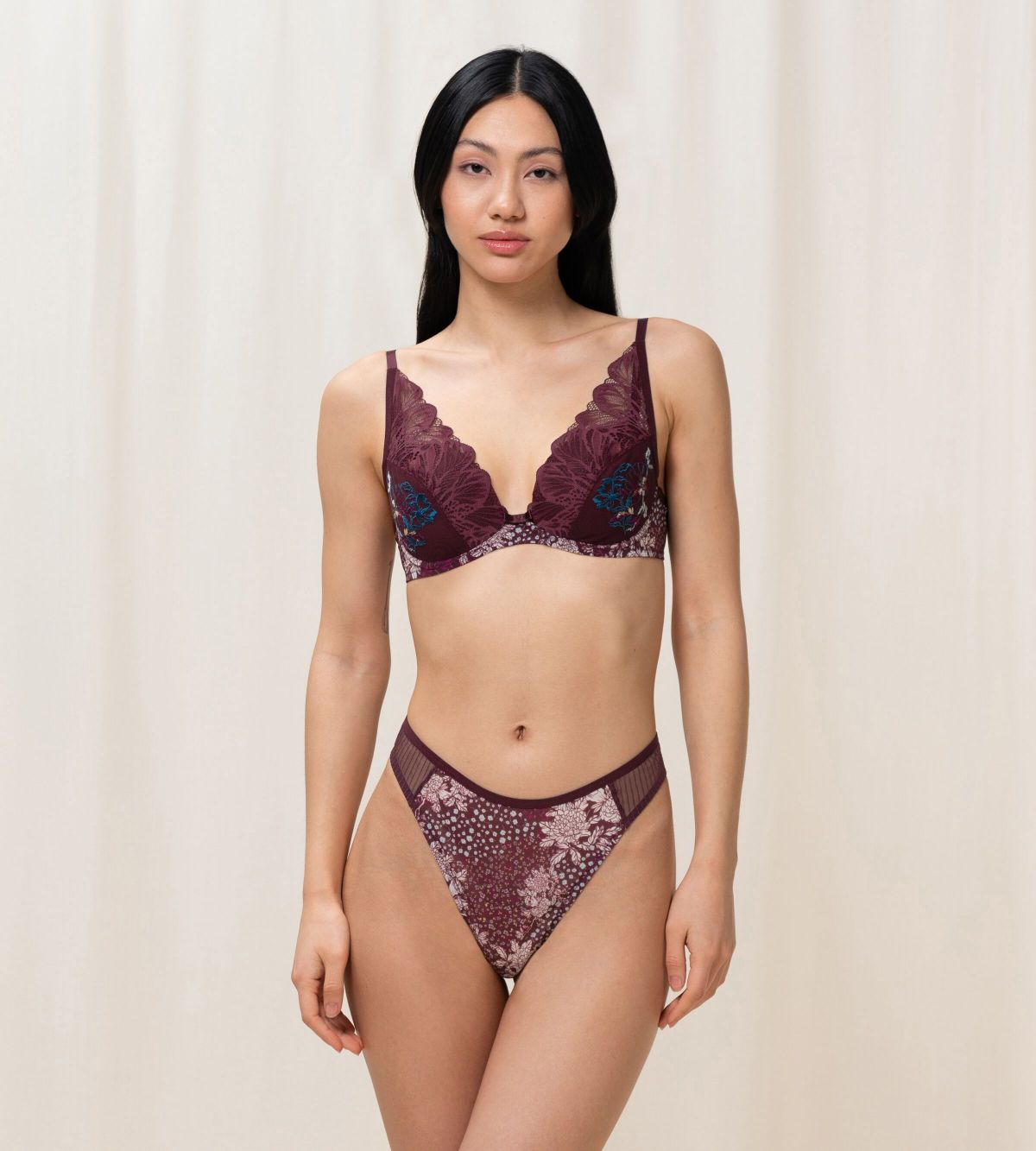 Triumph Lavish Spotlight burgundy wired padded bra Model full front view, highlighting the detailed lace embroidery and elegant plunge fit. Now Online at Blue Salon Qatar