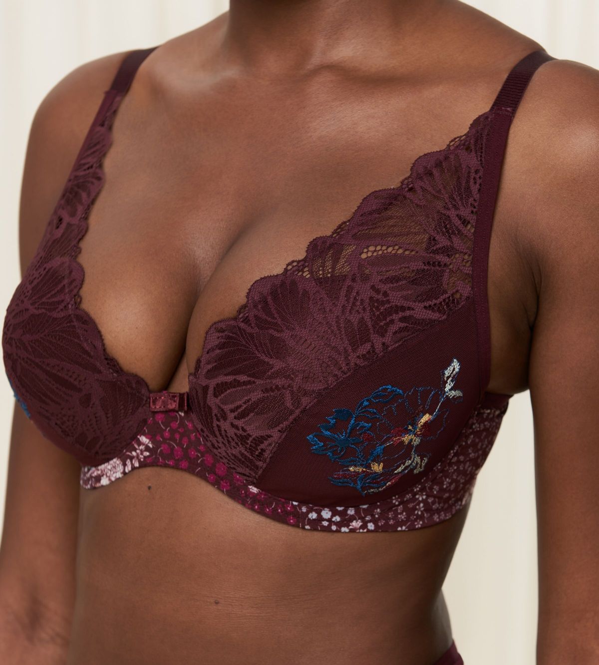 Triumph Lavish Spotlight burgundy wired padded bra second model close-up view, highlighting the detailed lace embroidery and elegant plunge fit. Now Online at Blue Salon Qatar