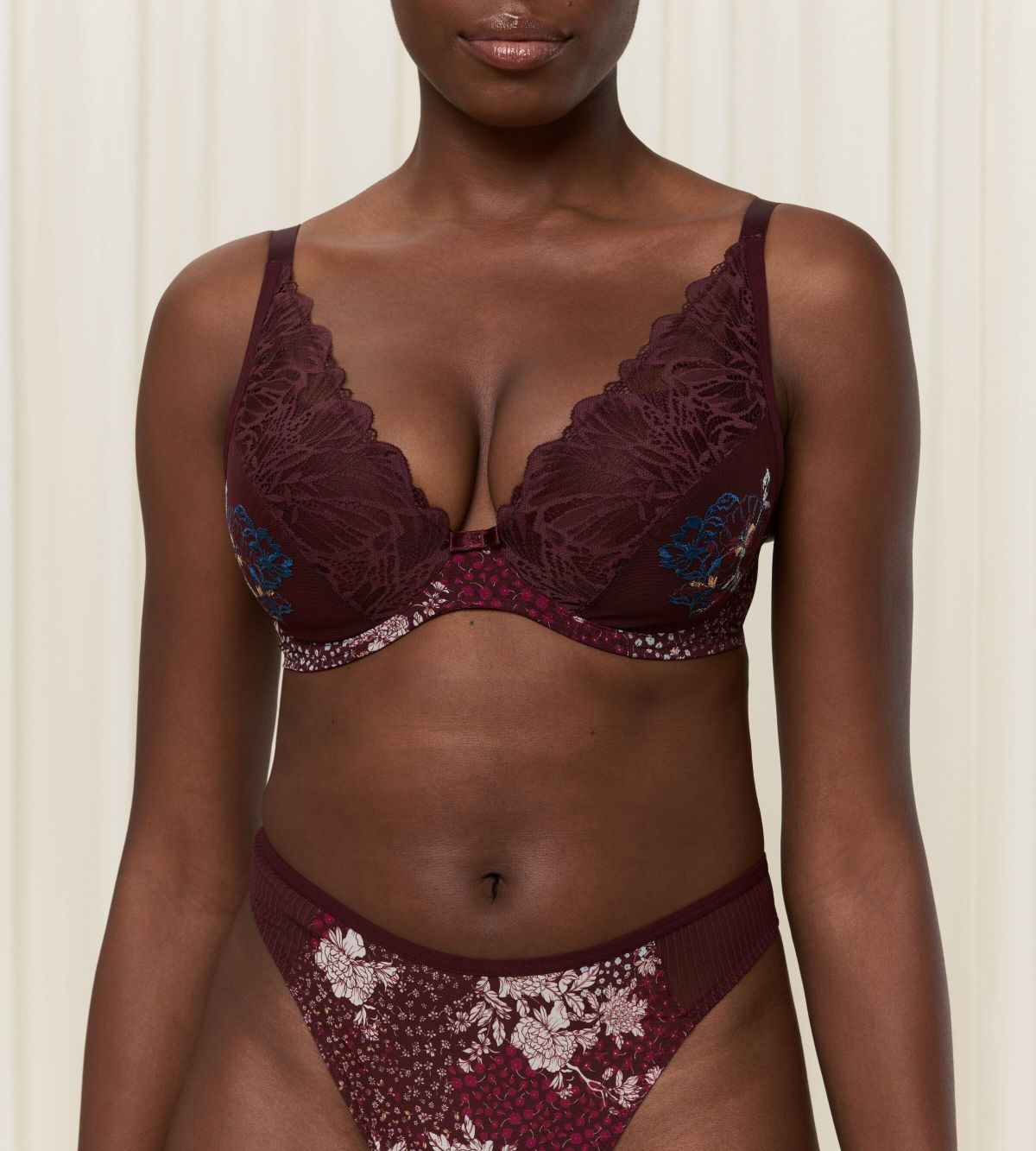 Triumph Lavish Spotlight burgundy wired padded bra second model front view, highlighting the detailed lace embroidery and elegant plunge fit. Now Online at Blue Salon Qatar