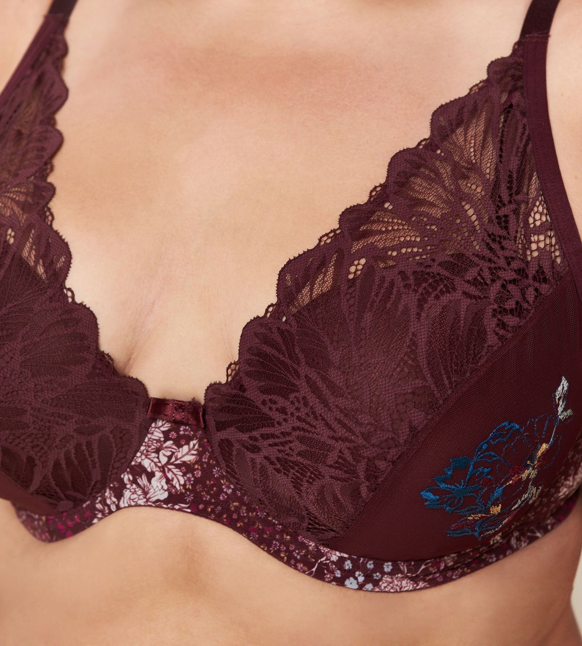 Triumph Lavish Spotlight burgundy wired padded bra third model close-up view, highlighting the detailed lace embroidery and elegant plunge fit. Now Online at Blue Salon Qatar