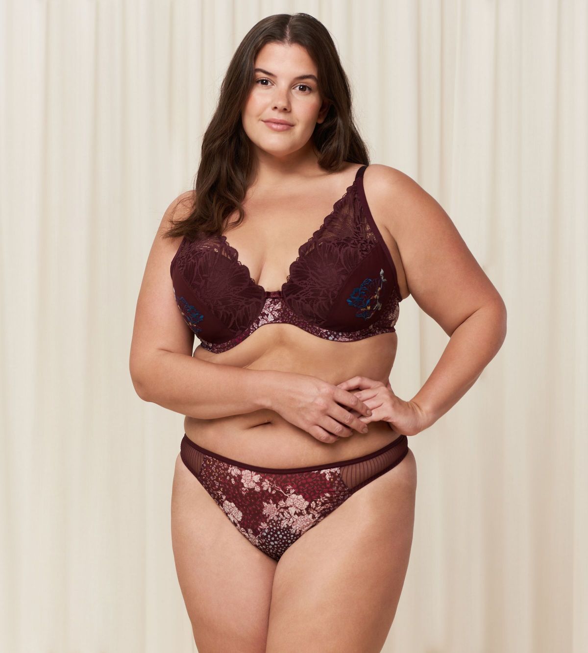 Triumph Lavish Spotlight burgundy wired padded bra third model full front view, highlighting the detailed lace embroidery and elegant plunge fit. Now Online at Blue Salon Qatar