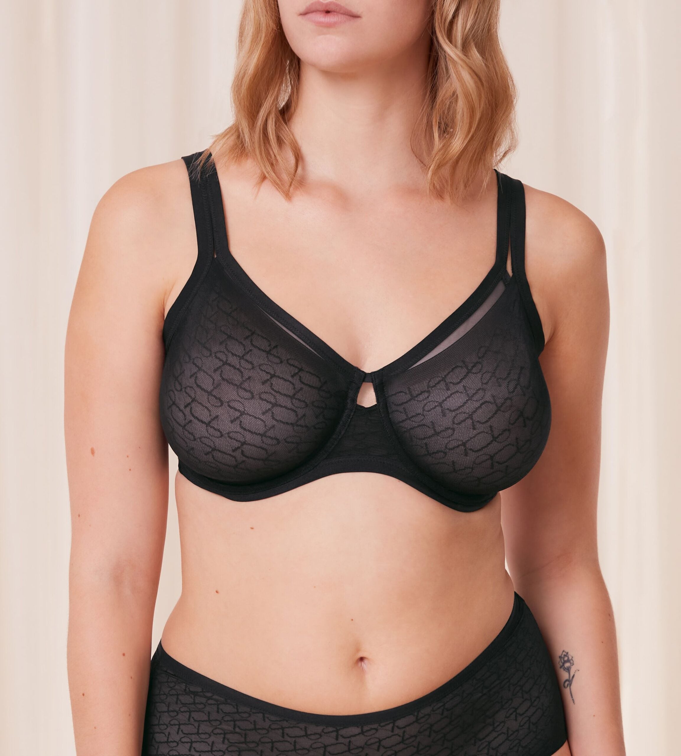 Triumph Signature sheer black minimizer bra model front view, with geometric monogram pattern. Available for Online Purchase