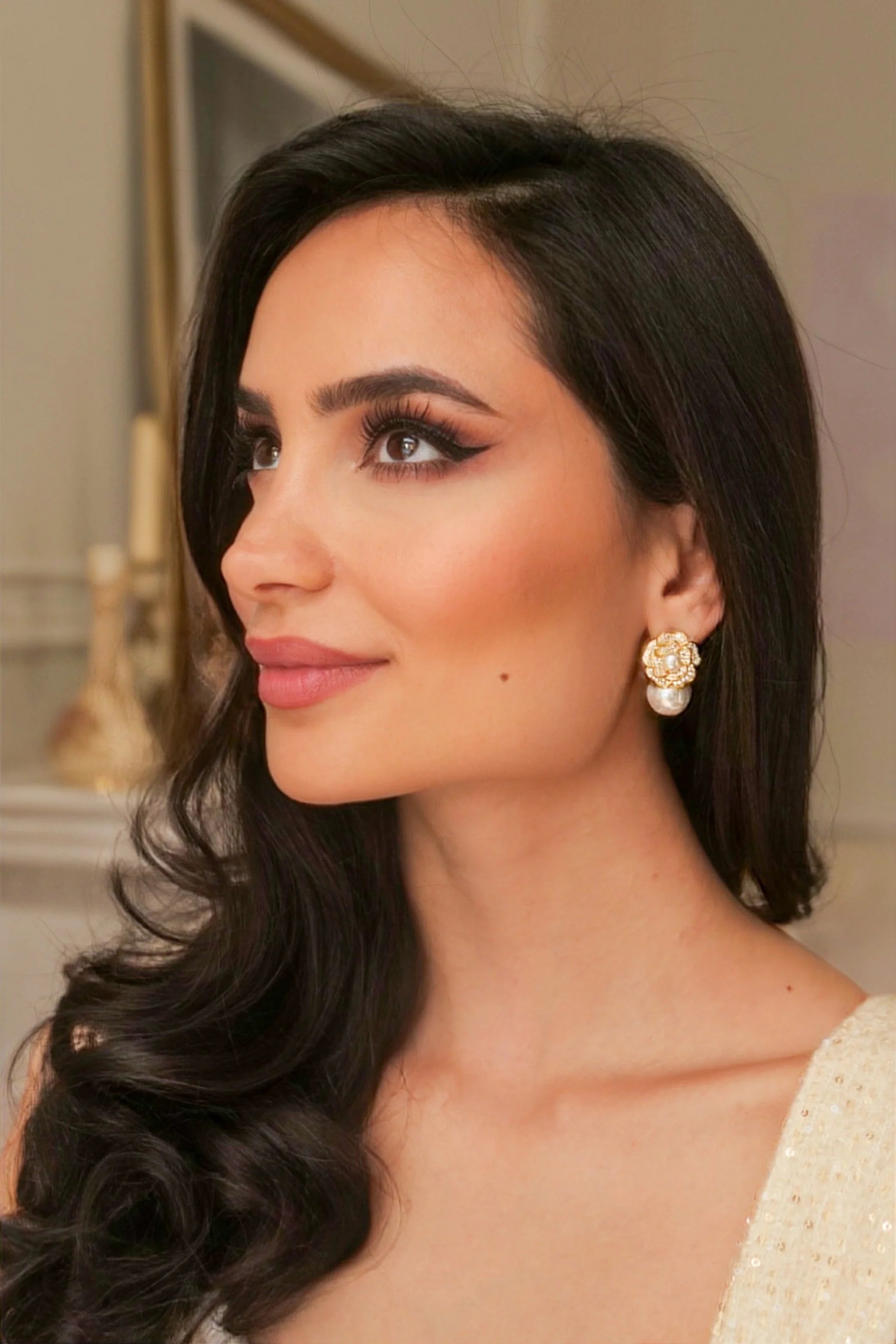 Gold-toned flower stud earring with intricate details and a large white pearl drop.