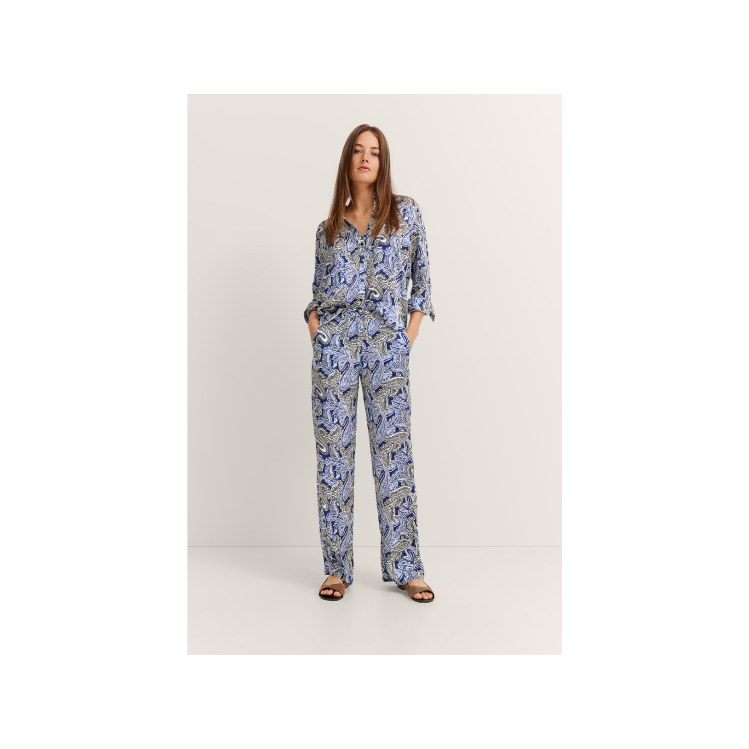 Loose-fitting navy blue women's trousers with a light blue and grey paisley print, featuring straight legs and side pockets.