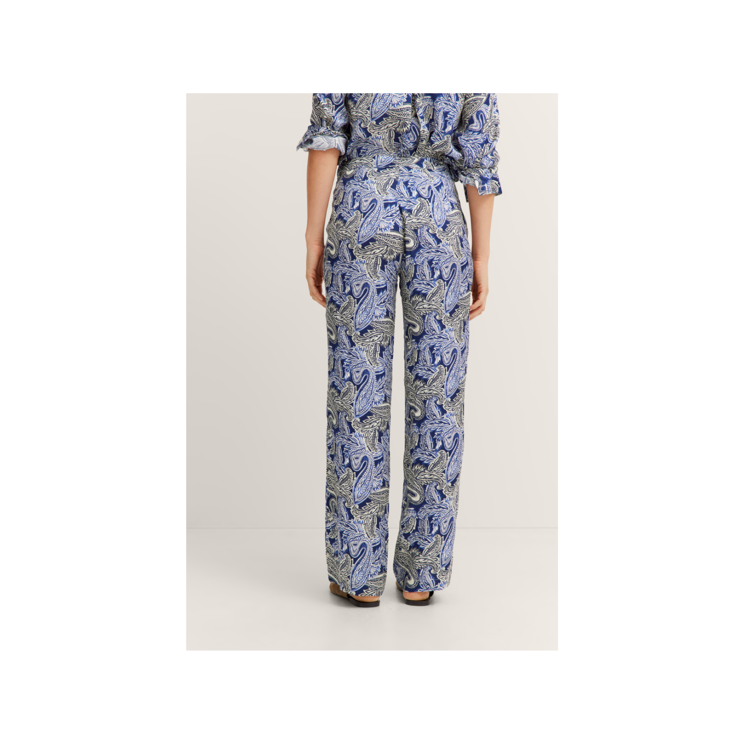 Navy blue women's trousers with a light blue, white, and grey paisley pattern. Straight-leg, flowy style.