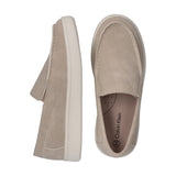 Beige slip-on sneakers with moccasin stitching and thick cream soles. One shoe shows a 'ck' logo and 'Calvin Klein' on the in