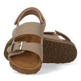 Beige sandals with two front straps, one with a silver-toned buckle and embossed CK logo. Velcro ankle strap. Cork footbed, b