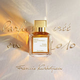 Rectangular clear glass perfume bottle with amber liquid, a gold-toned rectangular cap, and a white label on the front.