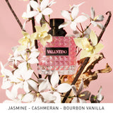 Valentino Born In Roma Donna EDP - 50ml Valentino perfume bottle surrounded by flowers and vanilla beans on a pink background