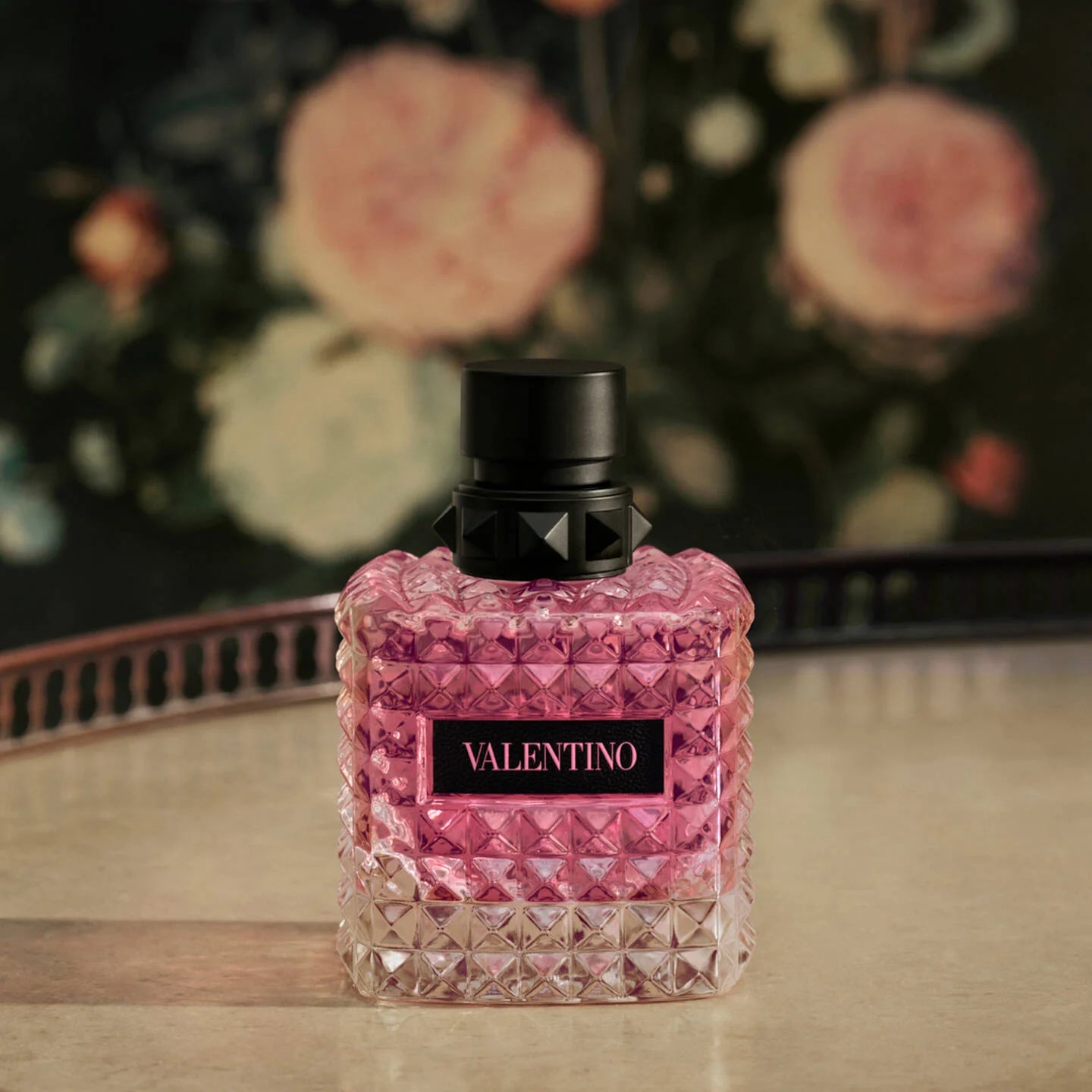 Valentino Born In Roma Donna EDP - 50ml PinkValentino perfume bottle on a wooden surface with a floral background