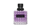 A Valentino Donna Born In Roma Stravaganza fragrance bottle in a striking purple hue. The glass features the signature all-over pyramid rockstud texture with a clear-to-purple gradient, topped with a matte black cap and a black leather-style label with purple Valentino branding.
