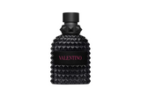 An all-black Valentino Uomo Born In Roma Rockstud Noir fragrance bottle featuring the signature pyramid-studded glass design, a matte black cap with a studded collar, and a black textured label with "VALENTINO" printed in contrasting pink text.