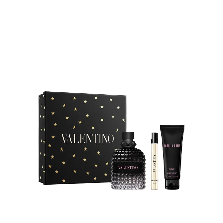 A Valentino Uomo Born In Roma men's gift set featuring a 100ml black rockstud glass fragrance bottle, a 15ml travel spray, and a 75ml tube of shower gel, displayed next to a black gift box embellished with gold stars and the Valentino logo.