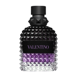 A close-up of a Valentino Uomo Born In Roma Stravaganza fragrance bottle. The glass features the signature rockstud pyramid texture with a gradient transitioning from clear at the base to a vibrant purple in the middle and a deep, translucent black at the top. It is finished with a matte black cap and a black leather-style label with purple branding.