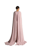 Back View of A woman modeling a Velvety brand evening gown in ORCHID ICE featuring a pleated V-neck bodice, a long silver-sequined column skirt, and dramatic floor-length cape sleeves.