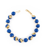 A necklace composed of royal blue enamelled spherical orbs, some featuring irregular gold-toned textured sections, with a gol