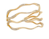 Gold-plated multi-band cuff bracelet with wavy design and pave-set clear crystals along the curves.
