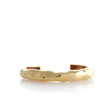 Gold-toned open cuff bracelet with a wide band and an irregular, hammered, wave-like surface texture.