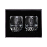 A luxury dark grey gift box displaying two diamond-cut shot glasses nestled securely in black protective foam.