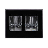 A luxury grey textured gift box containing two crystal whiskey glasses securely held in a black foam compartment.