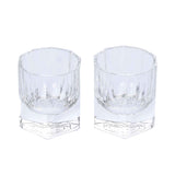A pair of clear, weighted lowball whiskey glasses with a geometric hexagonal base and vertical light-refracting cuts