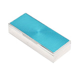 An angled shot highlighting the reflective silver surface and the intricate engraved spiral detail of the turquoise lid.