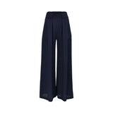 Front view of a pair of women's Momonì wide-leg trousers in solid navy blue, showcasing a flat high waistband and deep, structured box pleats that drape down to a fluid, loose hemline.