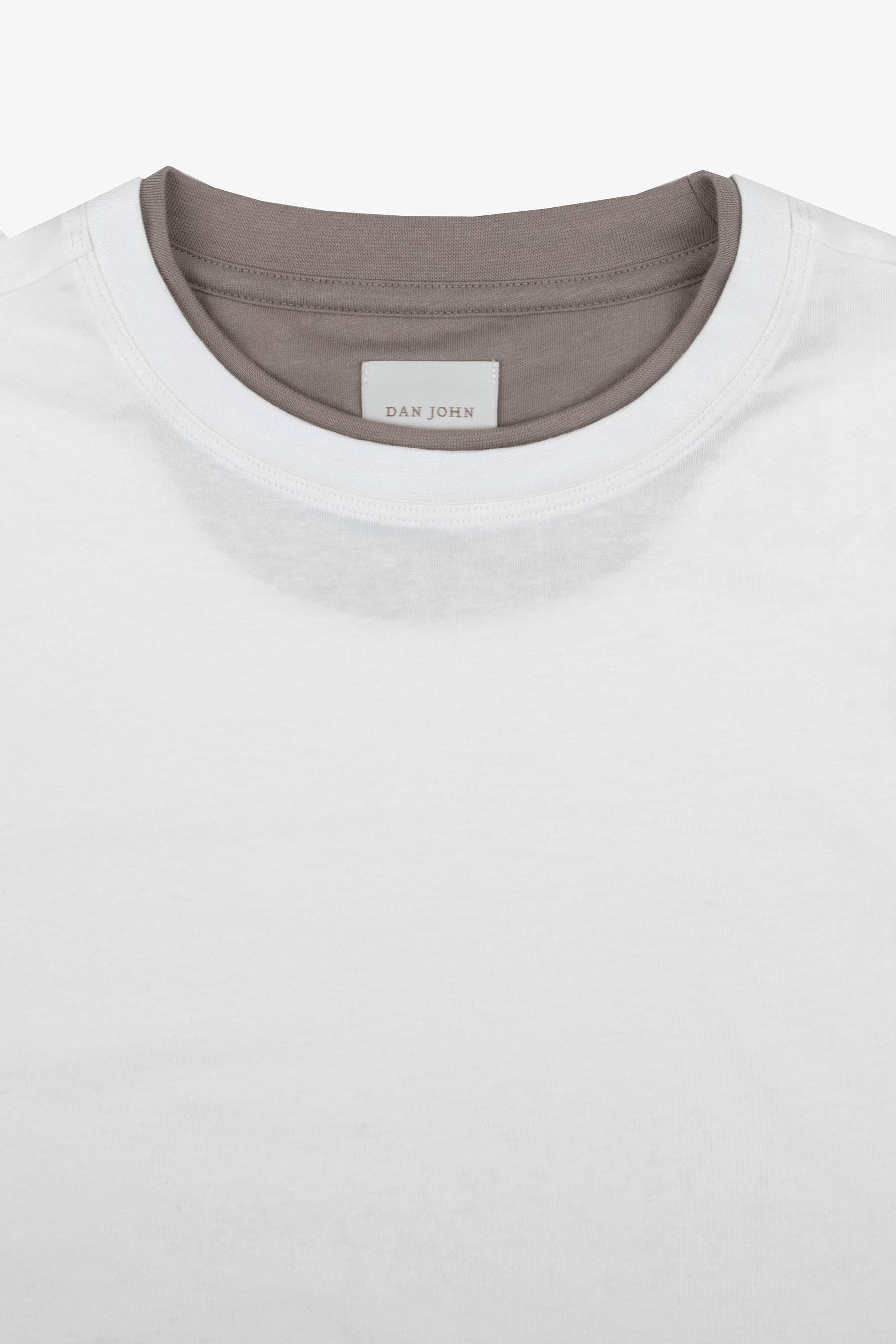 Off-white short-sleeve t-shirt with a ribbed crew neck. It features a brown mock neck visible underneath, with a 'DAN JOHN' l