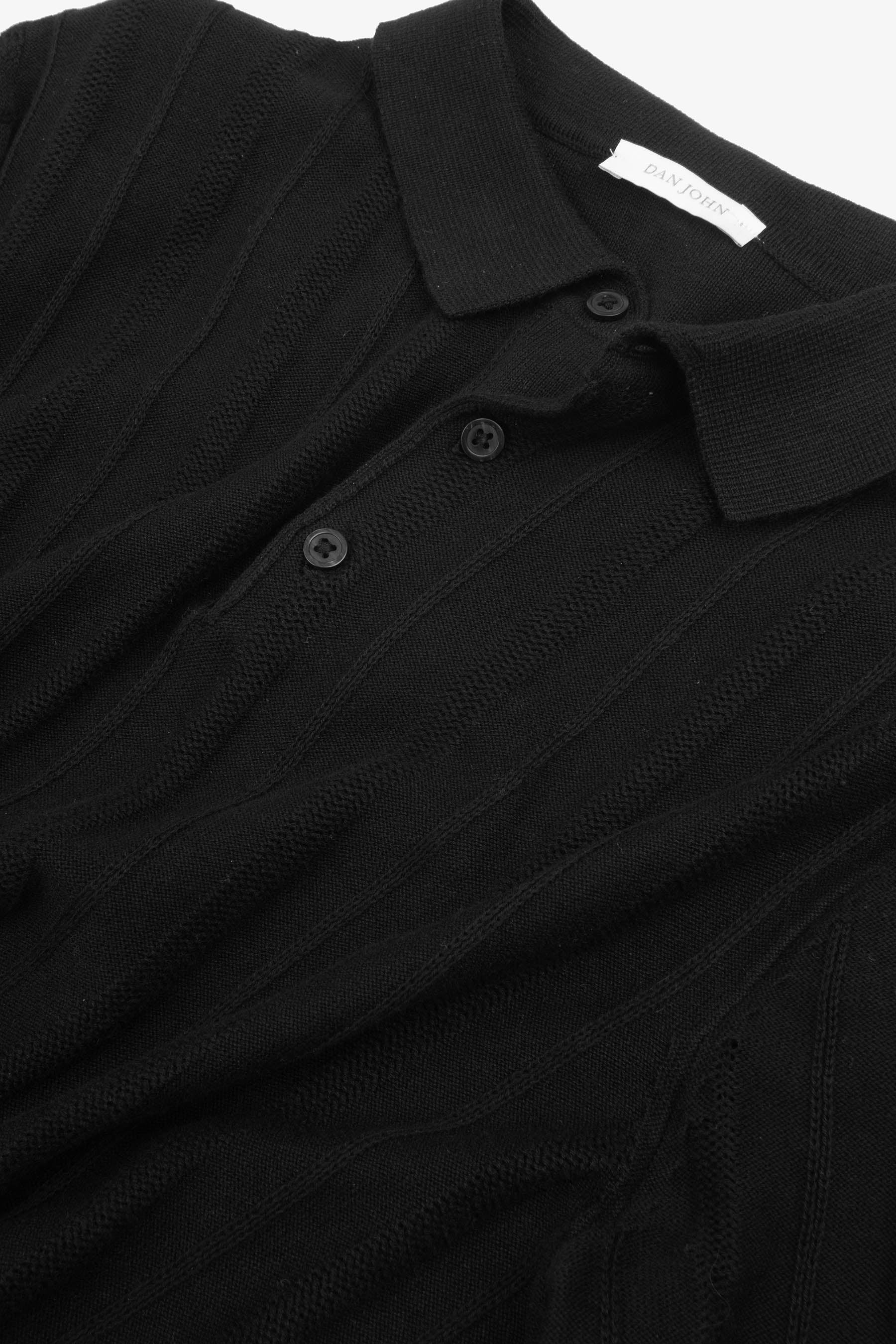 Black knit short-sleeve polo shirt with a ribbed collar, three-button placket, and vertical ribbed texture on the body.